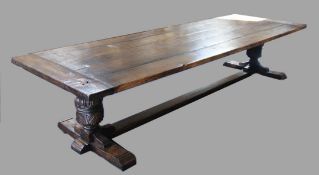 A large and impressive 17th century style oak refectory table, with planked top, on foliate carved