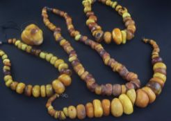 Four large amber bead necklaces of disc or pebble form and an amber pendant, with metal clasps,