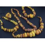 Four large amber bead necklaces of disc or pebble form and an amber pendant, with metal clasps,