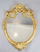 A Victorian giltwood and gesso wall mirror, with tasselled floral crest and bevelled oval plate, W.