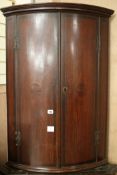 A George III inlaid oak bowfronted hanging corner cupboard, W.72cm