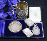 A late Victorian embossed silver christening mug, two silver vestas and two silver medallions.