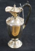 A silver urn-shaped hot water jug, the ebonised handle with acanthus terminals, London 1915,