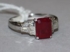 A modern 18ct white gold, ruby and diamond ring, with central emerald cut ruby, flanked by