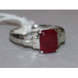 A modern 18ct white gold, ruby and diamond ring, with central emerald cut ruby, flanked by