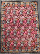 A large Kelim carpet, with polychrome floral field on a puce ground, 11ft 2in by 8ft 1in.