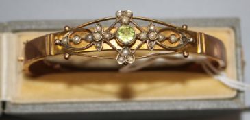 A George V 9ct gold, peridot and seed pearl set hinged bangle, in box.