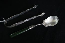A pair of George III sugar tongs and an American silver and nephrite handled preserve spoon.