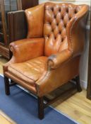 A pair of button back leather wing armchairs