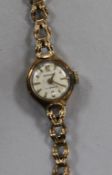 A lady's 9ct manual wind wrist watch on a 9ct gold bracelet.