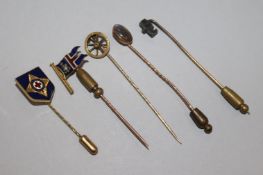 A 9ct gold and enamelled stock pin, two yellow metal stock pis and two other pins.