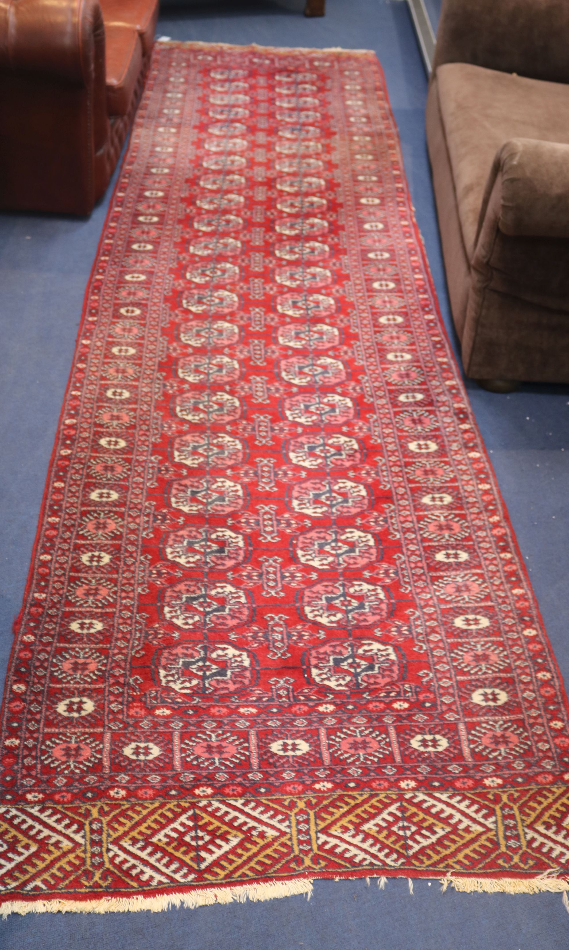 A Bokhara red ground runner, woven with two rows of elephants foot, 380cm x 95cm