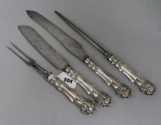 An ornate three piece plated handled carving set and a similar bread knife