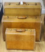 A graduated set of three 1940's-50's tan coloured suitcases