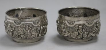 Two Burmese white metal Thabeik bowls of traditional form, embossed with deities and figures, each