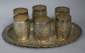 A set of six Indian white metal beakers and a tray, 44.6ozs, tray 35.5cm