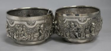 Two Burmese white metal Thabeik bowls of traditional form, embossed with deities and figures, each