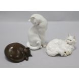 Two porcelain cats and one resin