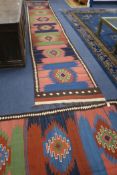 A Kelim long runner and two similar rugs, all with matching geometric design in indigo, green,