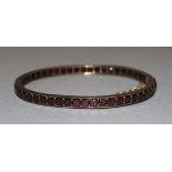 An Edwardian gold and garnet set hinged bangle,