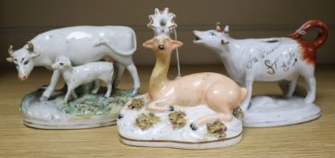 Three Staffordshire figures, a Walton-type recumbent 'Roe' buck, a cow creamer and a cow and calf