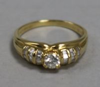 An 18ct gold and diamond ring, the central stone approx 0.25ct, flanked by baguette-set shoulders,