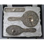 A cased 1970's repousse silver three piece dressing table set.