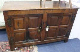 An oak dwarf cupboard fitted a pair of panelled doors, on stile feet, W.138cm