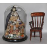 A Regency painted wood doll and accessories under glass dome and a miniature chair