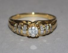 An 18ct gold and diamond ring, the central stone approx 0.25ct, flanked by baguette-set shoulders,