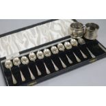 A cased set of eleven (ex 12) silver teaspoons and two silver napkin rings.