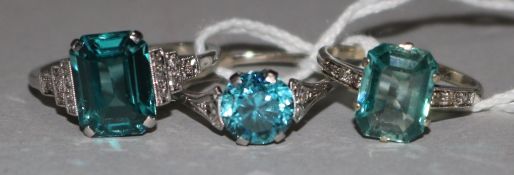 An 18ct white gold and blue zircon ring with diamond set shoulders and two other gem set rings,