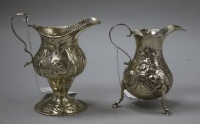 A George II silver baluster-shaped cream jug and a George III embossed silver helmet-shaped cream