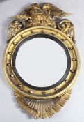 A Regency giltwood and gesso wall mirror, with circular bevelled plate and eagle crest, H.3ft 4in.