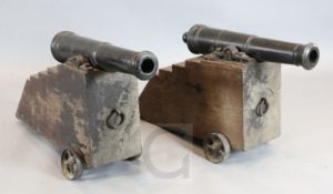 A pair of 19th century bronze signal cannons on stepped oak trunnions, with cast iron wheels,