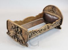 A Scottish Arts & Crafts carved elm cradle, decorated with birds, thistles and celtic scroll motifs,