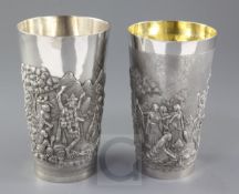 Two Indian white metal beakers, each embossed with scenes of women making offerings to Lord Shiva