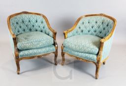 A pair of French carved beech fauteuil, with buttoned blue fabric upholstery, W.2ft 2in. H.2ft 8in.