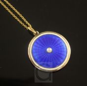 An Edwardian gold, blue guilloche enamel and split pearl circular pendant locket, on a 15ct gold