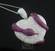 An 18ct white gold, pave set diamond, ruby set heart shaped pendant with entwined serpent, on a 14ct