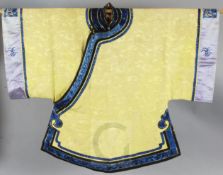 A Chinese yellow brocade jacket, the black satin borders embroidered with blue flowers