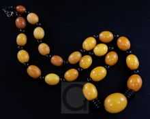 A single strand graduated amber bead necklace with ebonised bead spacers, gross 87 grams, 66cm.
