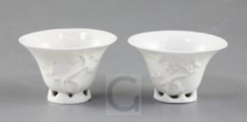 A pair of Chinese blanc-de-chine libation cups, Dehua, Kangxi period, each moulded with prunus