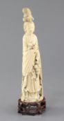 A Chinese ivory standing figure of He Xiangu, late 19th / early 20th century, holding a basket and a