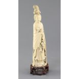 A Chinese ivory standing figure of He Xiangu, late 19th / early 20th century, holding a basket and a