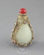A Chinese pale celadon jade, silver gilt and cabochon gem mounted snuff bottle, early 20th