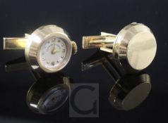 A pair of 14k gold circular cufflinks, one with inset timepiece and winding crown, the dial