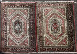 A pair of Qum silk rugs, with graduated octagonal motifs on a pink and green ground, 5ft 4in by