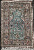 A Persian silk prayer rug, with central mihrab on a green ground, 4ft by 2ft 7in.