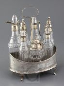 A George III silver oval boat shaped cruet stand, with wooden base, engraved decoration and seven